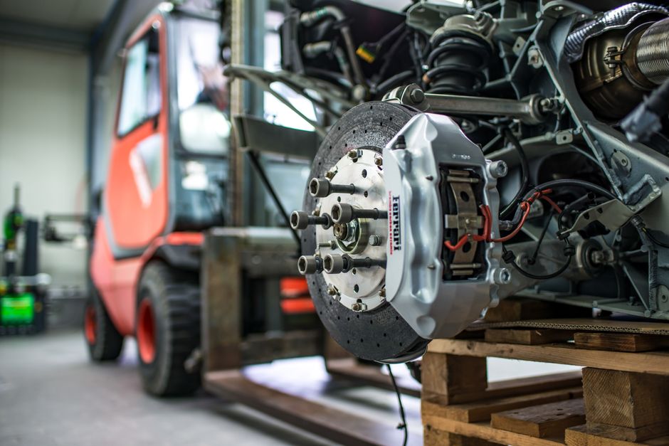 Professional technician inspecting exotic car brake and suspension system
